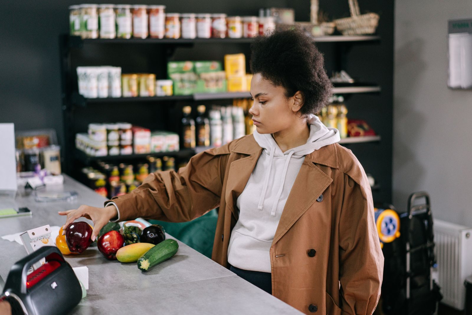 A woman selecting fresh fruits and vegetables at a grocery store with shelves stocked in the background