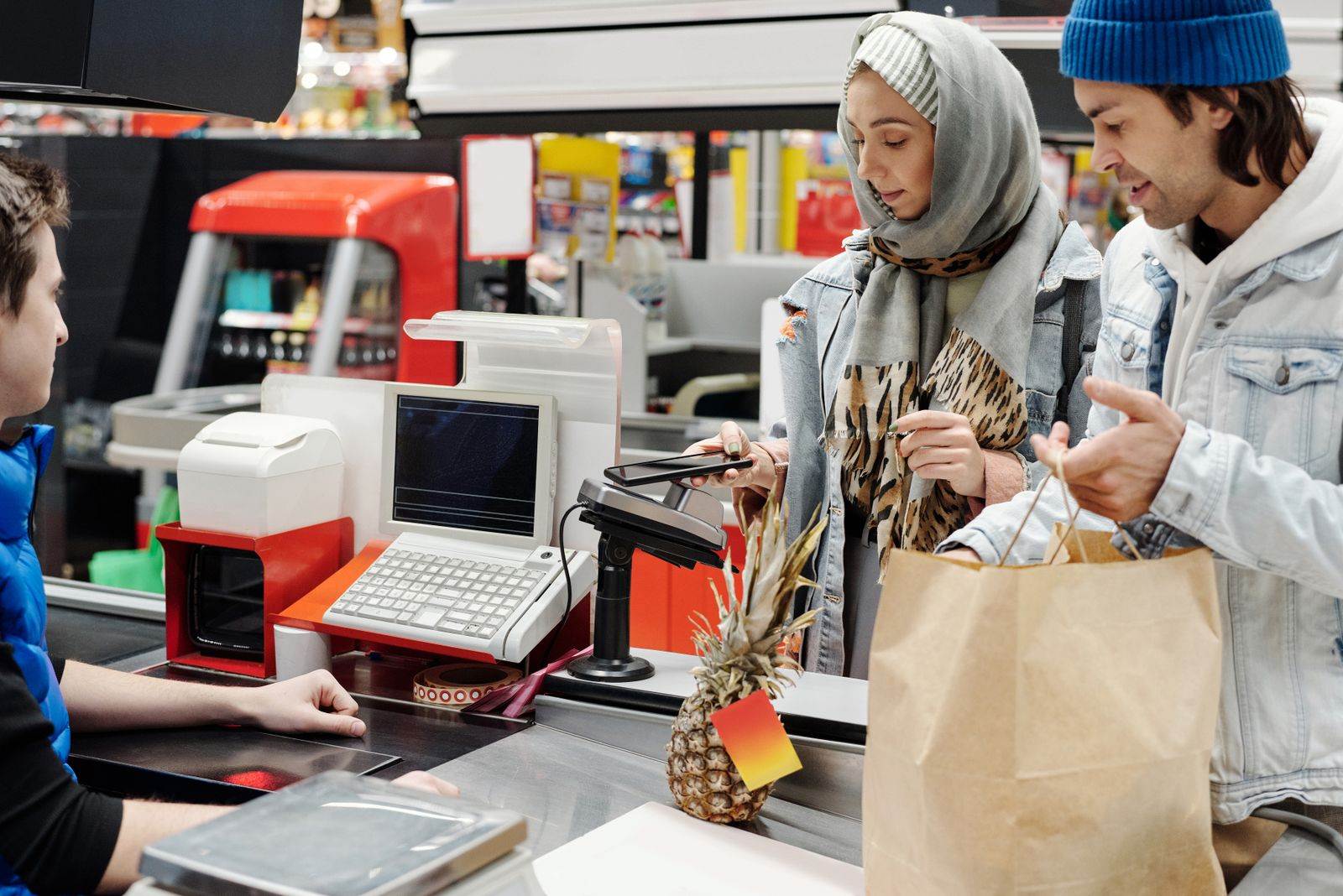 A couple in a supermarket checkout using mobile payment with a cashier. 