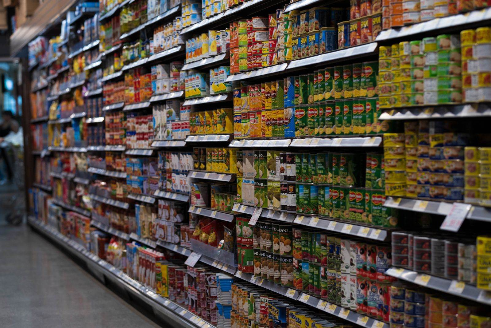 A supermarket aisle filled with various canned goods on shelves, showcasing retail diversity